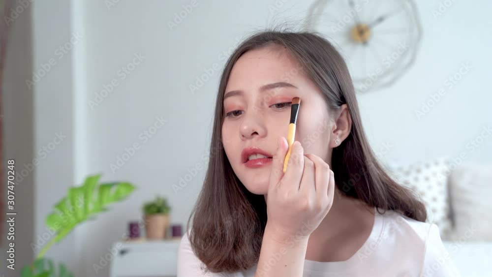 Beautiful Asian women makeup themselves by using a brush to apply Eyeliner Beautiful Asian women makeup themselves by using a brush to apply Eyeliner
