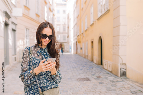 Woman talk by her smartphone in city. Young attractive tourist outdoors in italian city