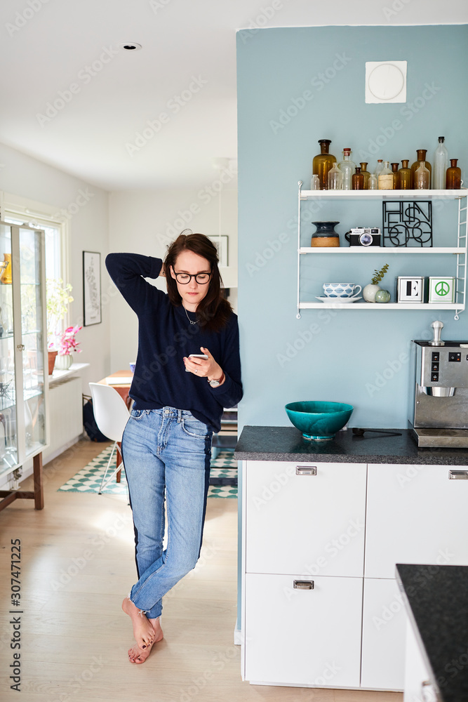 Woman using smartphone in kitchen Woman using smartphone in kitchen