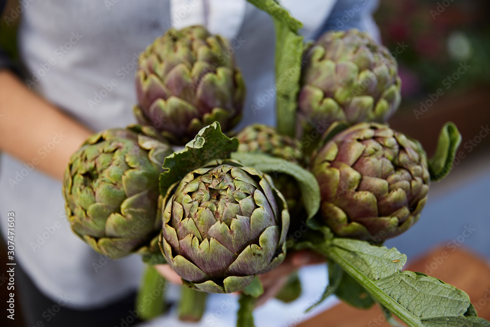 Person holding artichokes Person holding artichokes