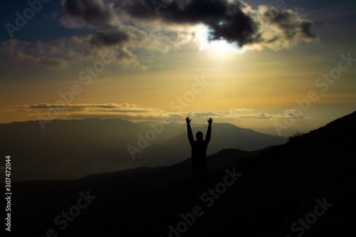 Man raised hands mountains on background. Young man traveling n the mountains. Travel Lifestyle concept.