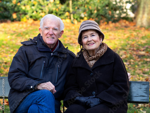 Senior couple smiling and looking at camera in Hyde Park, London. Autumn. Concept of positive