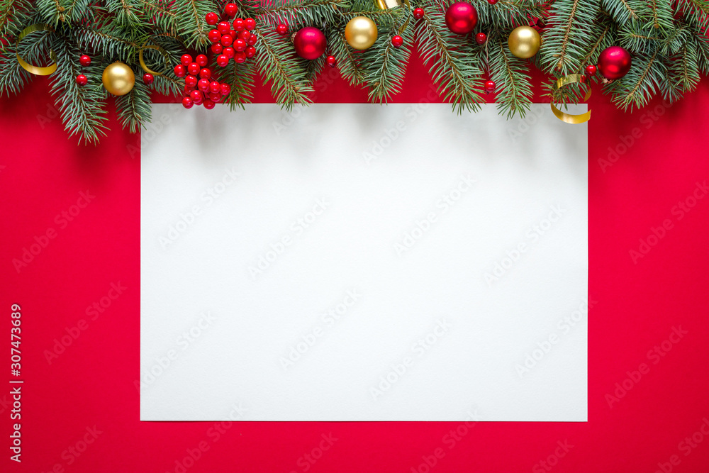 Christmas winter background.  Fir branches and holiday decorations, white paper with copy space for text on a red background, top view