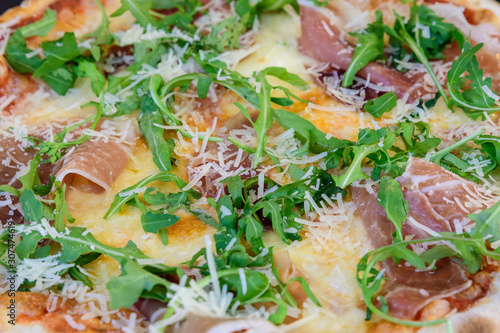 Traditional Italian pizza with prosciutto and rucola (arugula or salad rocket) displayed for sale at a street food market festival in Bucharest, Romania