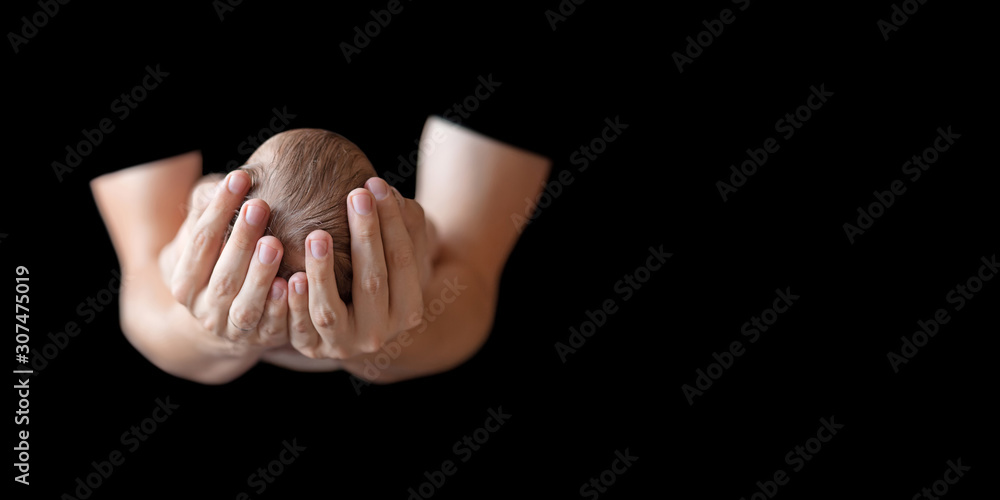 Fototapeta premium Father holding head of his newborn baby in hands on black background. Loving father hands holding cute sleeping newborn baby child. Close up picture with copy space