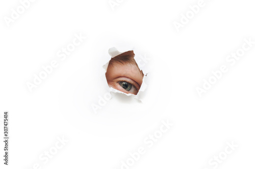 The eye. Voyeurism. The man is watching the wife. A curious look. Jealousy, spying on or overhearing the concept. Hole on White paper. photo