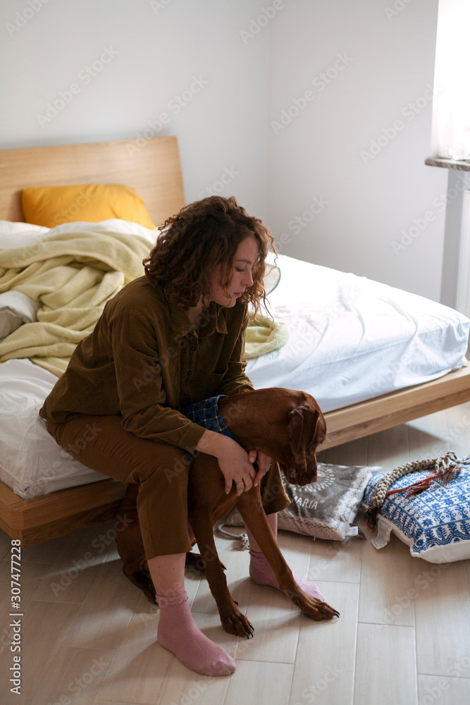 the girl is sitting on the bed hugging the dog herself the girl is sitting on the bed hugging the dog herself