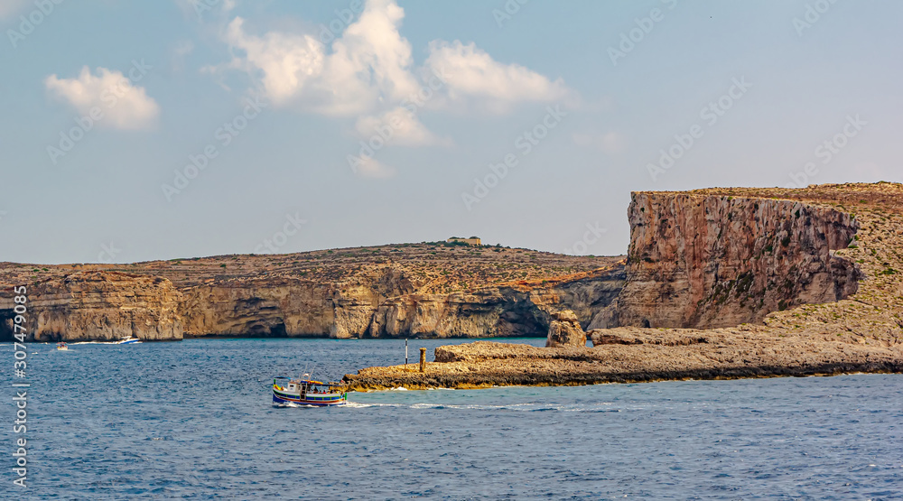Tourist boat riding in the Mediterranean Sea by the Comino Island, small island of the Maltese archipelago.