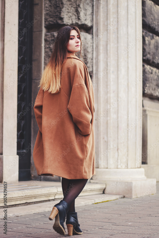 Model in black dress and long brown coat. Trench. Style. Fashion trends 2020. Hair with ombre. Business lady. Blogger. Work
