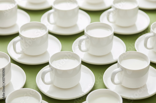 White cups of milk on green backdrop photo