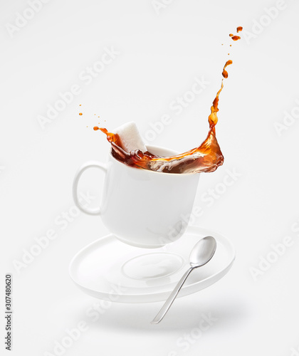 Falling cup with splashing coffee and sugar