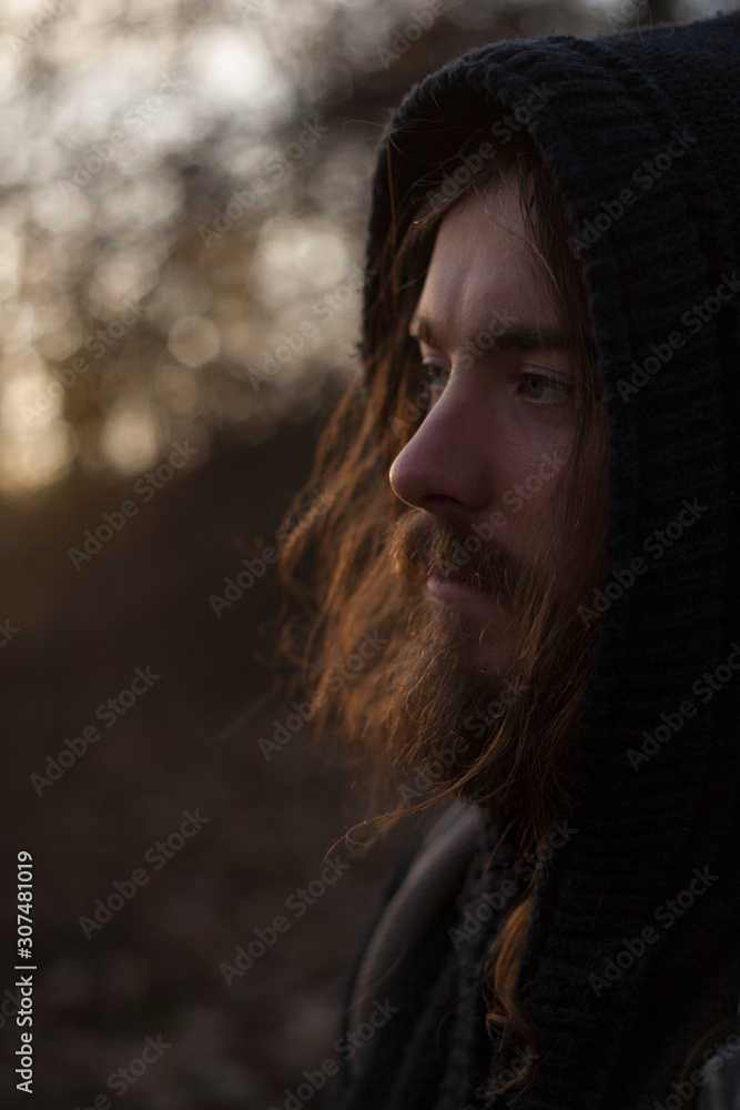 portrait of a guy in a hood with long hair and a beard at sunset Stock  Photo | Adobe Stock