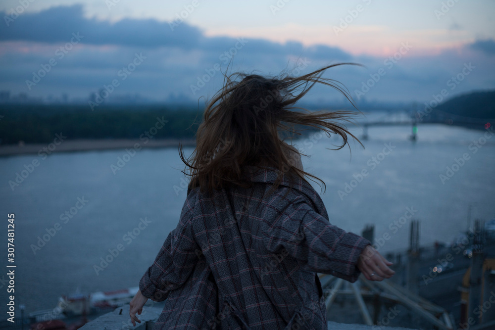 portrait of a running girl with long hair against the backdrop of the river and the night city wind blows portrait of a running girl with long hair against the backdrop of the river and the night city wind blows