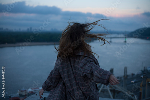portrait of a running girl with long hair against the backdrop of the river and the night city wind blows