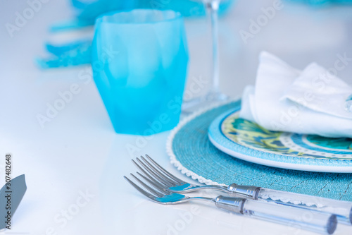 Closeup shot of the serving of a dinner table with blue utensils on a blurred background