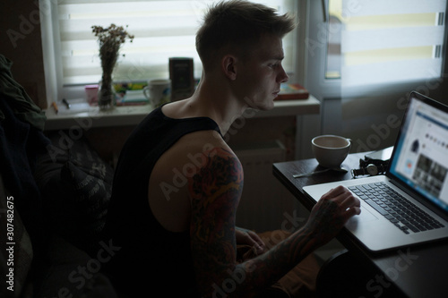 portrait of a guy in a shirt working behind a laptop photo
