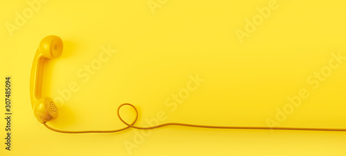 A yellow vintage dial telephone handset with yellow background.