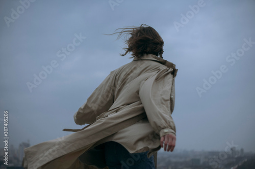 Rear view of woman in coat standing against sky at dusk photo