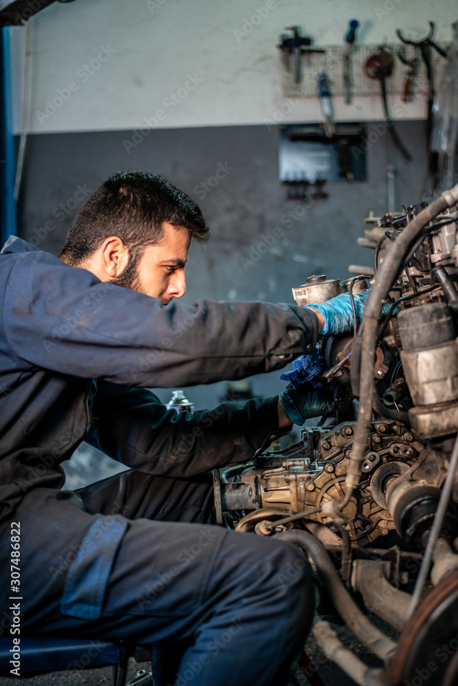 Car service and maintenance: an automechanic is repairing a vehicle Car service and maintenance: an automechanic is repairing a vehicle