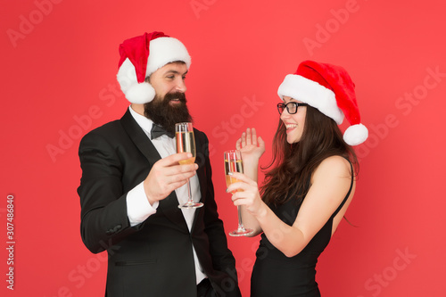 Winter celebration. Merry christmas. Colleagues at office party. Couple at corporate party. Happy new year. Bearded businessman in tuxedo and girl drinking sparkling wine red background. Winter party