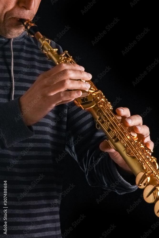 Fototapeta premium soprano saxophone in the hands of a guy on a black background