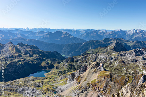 View from the summit of Rote Wand mountain (Vorarlberg, Austria). Wild alpine landscape with rocky mountains, forest and a lake under blue sky. © Andreas Föll