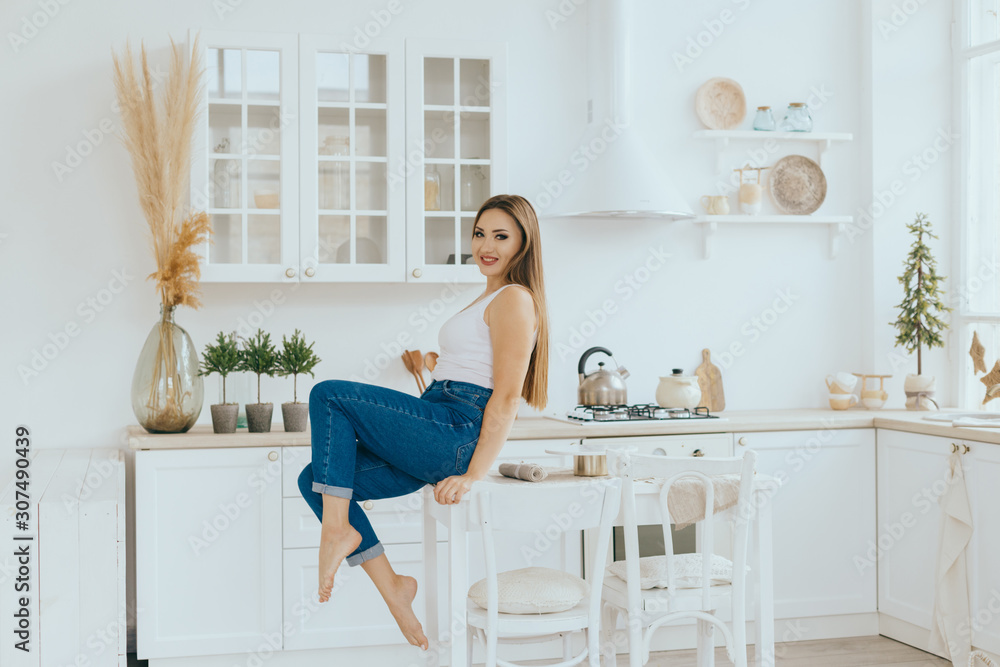 Portrait of a smiling young housewife in modern bright minimalistic Scandinavian kitchen Portrait of a smiling young housewife in modern bright minimalistic Scandinavian kitchen