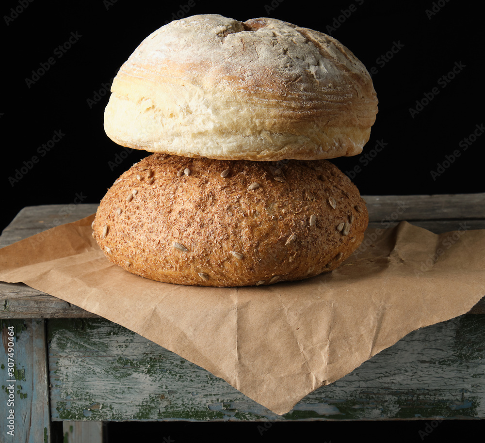 two loaves of baked round bread lay on brown paper