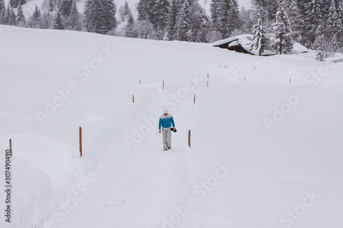 Mann läuft in verschneiter Winterlandschaft einen Weg entlang