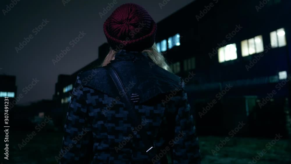 girl looks through the windows of the factory at night girl looks through the windows of the factory at night