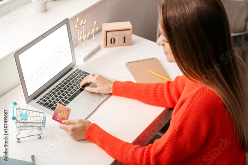 Young woman with credit card and computer shopping online at home