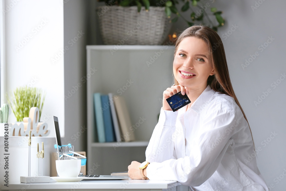 Young woman with credit card and computer shopping online at home Young woman with credit card and computer shopping online at home