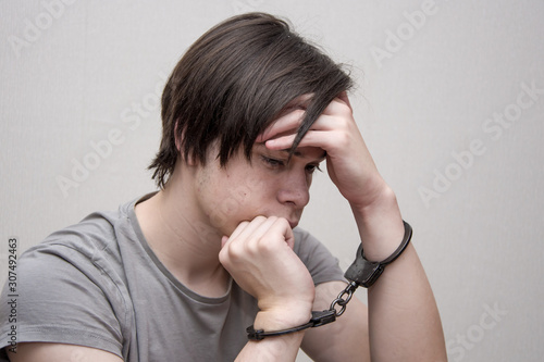 Принти на полотні A handcuffed teenager sits on a grey background