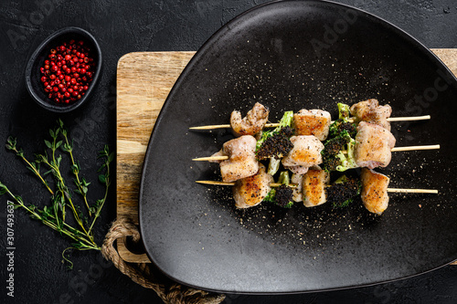 Barbecued chicken breast skewers. broccoli. Black background. Top view