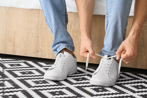 Young man putting on shoes at home photo