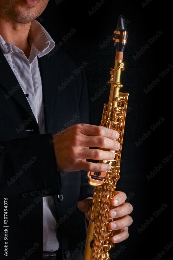 Fototapeta premium soprano saxophone in the hands of a guy on a black background