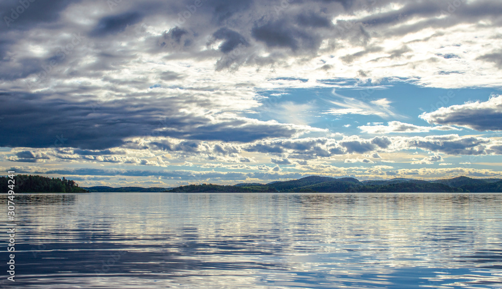 Beautiful sky and its reflection on the lake. Mirror summer lake. Ladoga Lake in Karelia. Russia