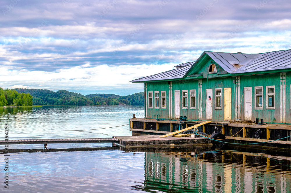 Beautiful sunset with reflection in the water on Ladoga Lake. Mirror summer lake with an old house. Karelia, Russia