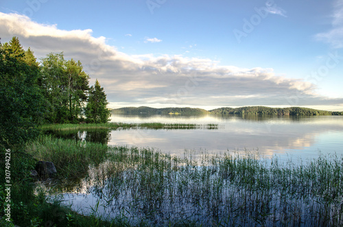 Reflections of a cloudy sky on a lake. Mirror summer lake. Ladoga Lake in Karelia. Russia