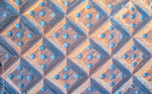 Texture of an old door. Fragment of a beautiful antique door with metal rivets. Squares. Vintage background.