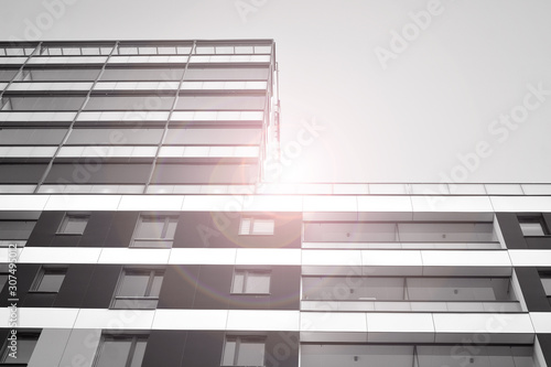 Detail of modern residential flat apartment building exterior. Fragment of new luxury house and home complex. Glass surface with sunlight. Black and white.