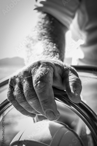 Φωτογραφία A sailor hand on the tiller on board his sailing boat in a black and white pictu