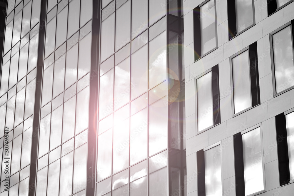 Modern office building wall made of steel and glass with blue sky. Glass surface with sunlight. Black and white. Modern office building wall made of steel and glass with blue sky. Glass surface with sunlight. Black and white.