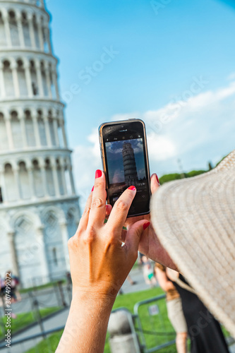 Tourist girl in Pisa, Italy. Woman photographing with mobile cell phone the historical monument