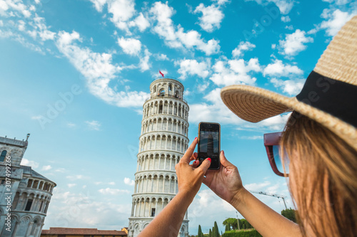 Tourist girl in Pisa, Italy. Woman photographing with mobile cell phone the historical monument