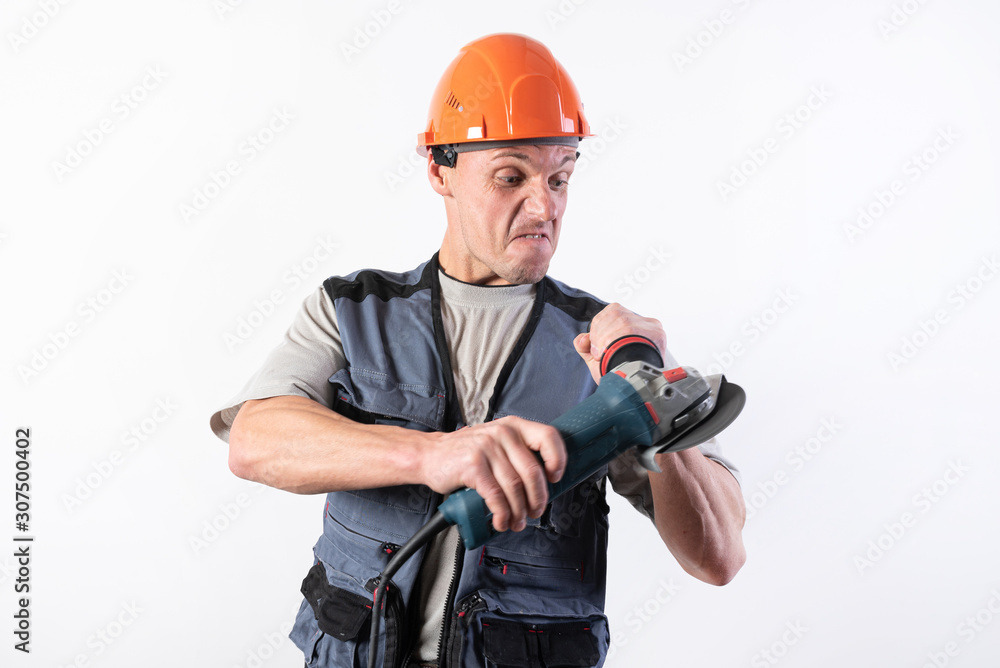 Builder with angle grinder, in a helmet, with a funny expression on his face. Builder with angle grinder, in a helmet, with a funny expression on his face.
