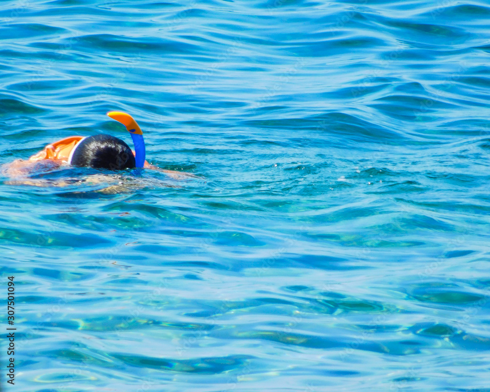 Enfant flottant sur l'eau en apnée avec masque dans la mer
