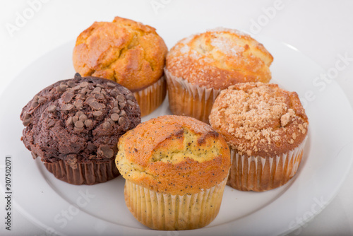 Assortment of freshly baked muffins on a white plate with isolated background