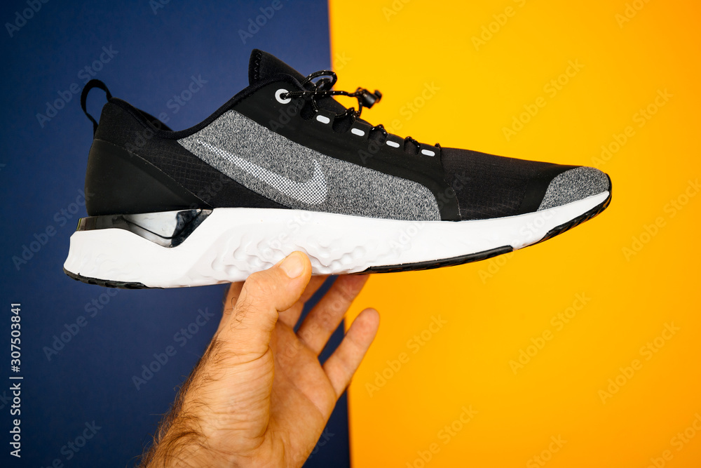 Paris, France - Oct 18, 2019: Man hand holding blue yellow background new  sport waterproof and windproof running shoe Nike Odyssey React Shield 2  side view Stock Photo | Adobe Stock