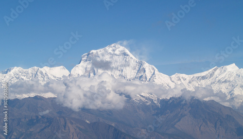 Amazing autumn panorama with mountains covered with snow and forest against the background of blue sky and clouds. Mount Everest, Nepal. © SP Kiran